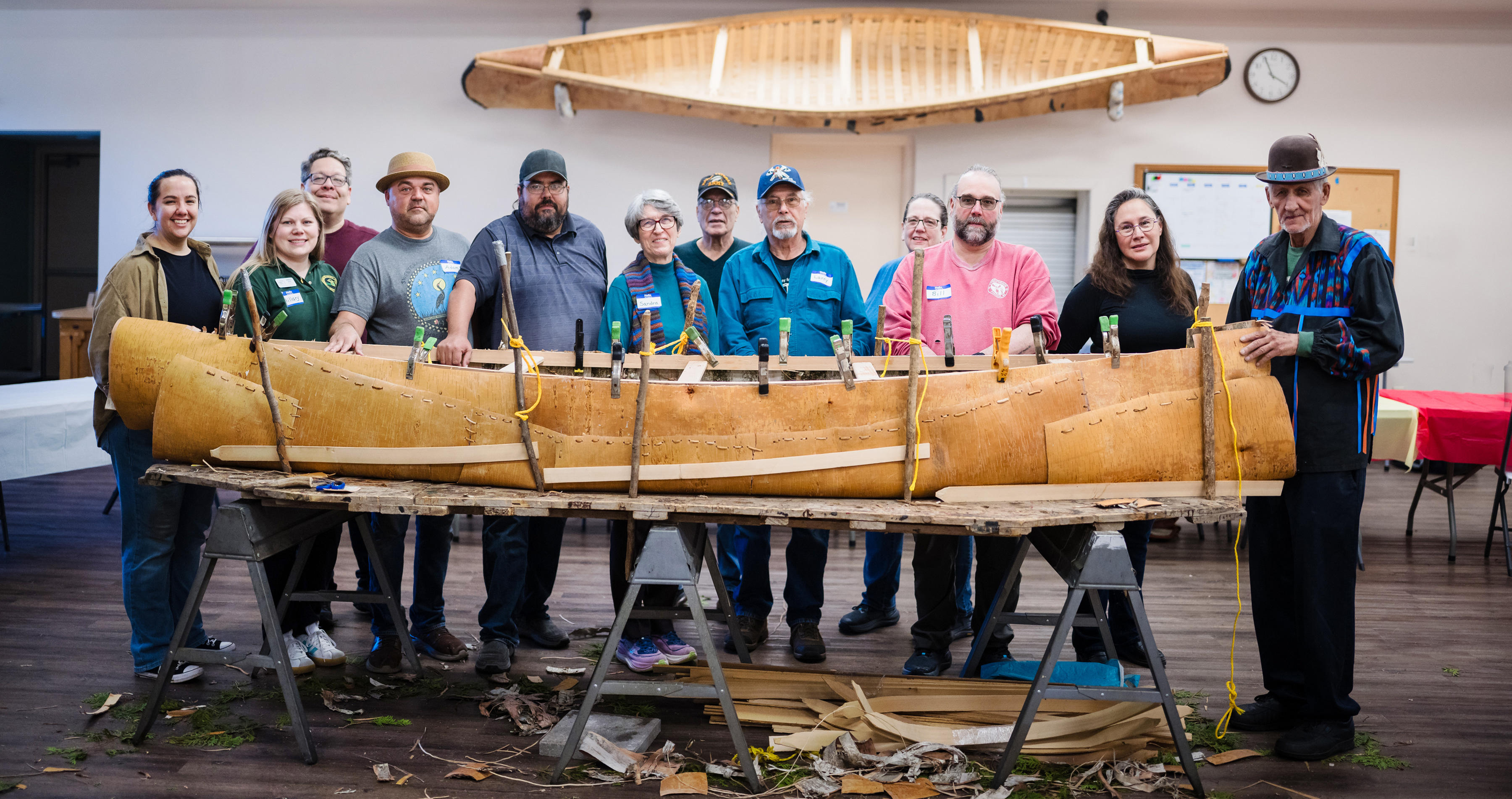 Participants stand with traditional birch bark canoe builder Ron Paquin (far right) after completing a canoe build in St. Ignace, Michigan, in April 2026. Photo courtesy of Cory Marie Podielski Photography
