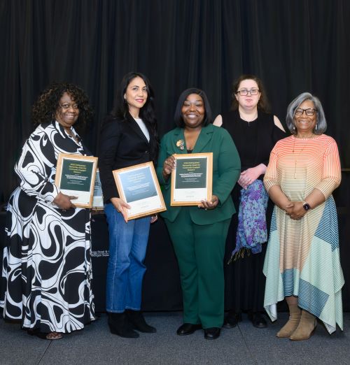 From left to right: Geneva Jackson, Elena Ruiz, Melvenna Fant-Jones, Kahlia Roberts, and Cassandra Coats standing side by side on a stage in front of a black curtain, smiling at the camera and holding award plaques.